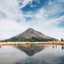 在晴朗的日子里，徒步旅行者来到湖边，湖水映衬着背后令人惊叹的山脉