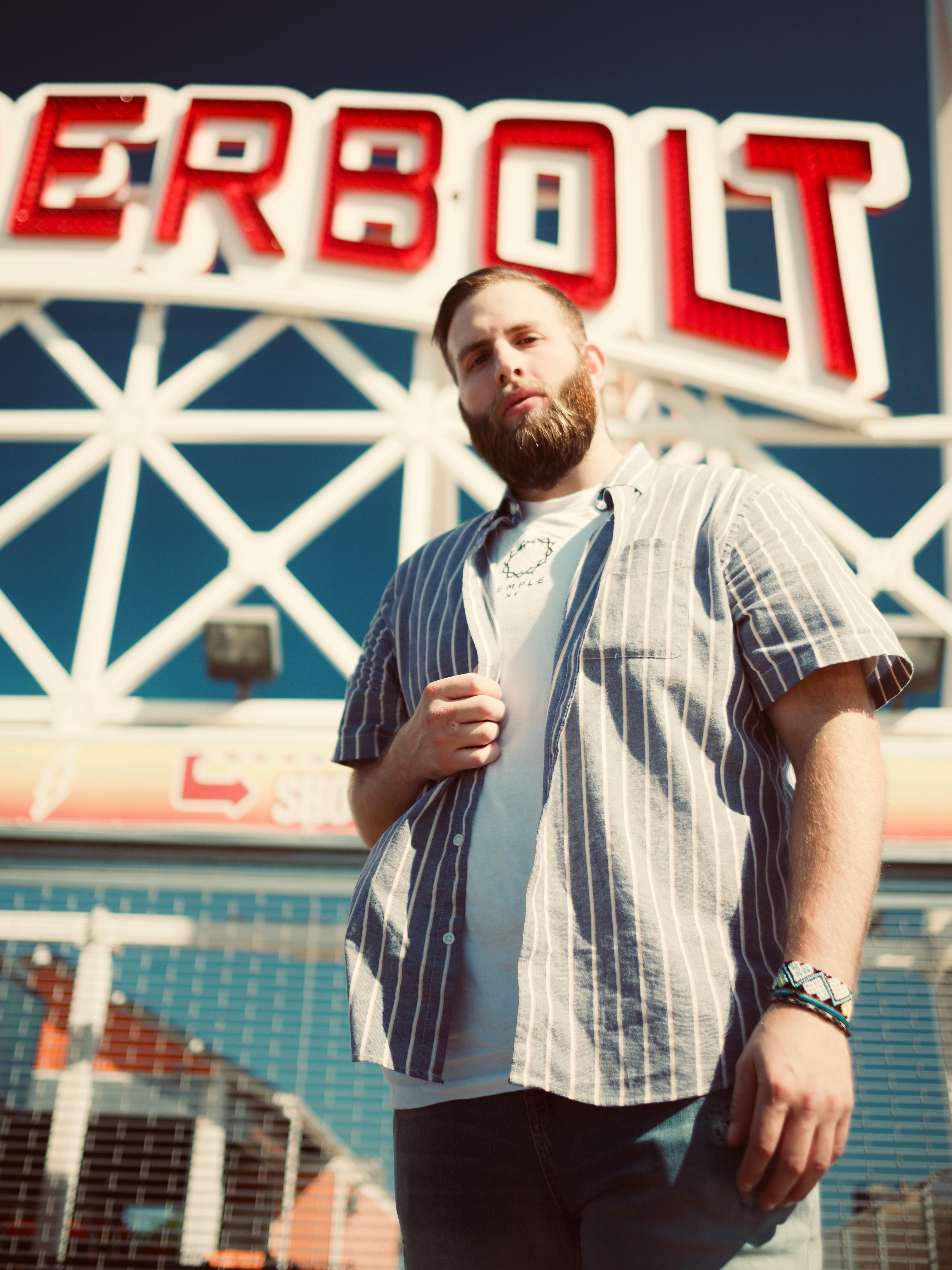 在一个阳光明媚的日子里，男子自信地在游乐园的标志性地标前摆好姿势