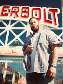 在一个阳光明媚的日子里，男子自信地在游乐园的标志性地标前摆好姿势