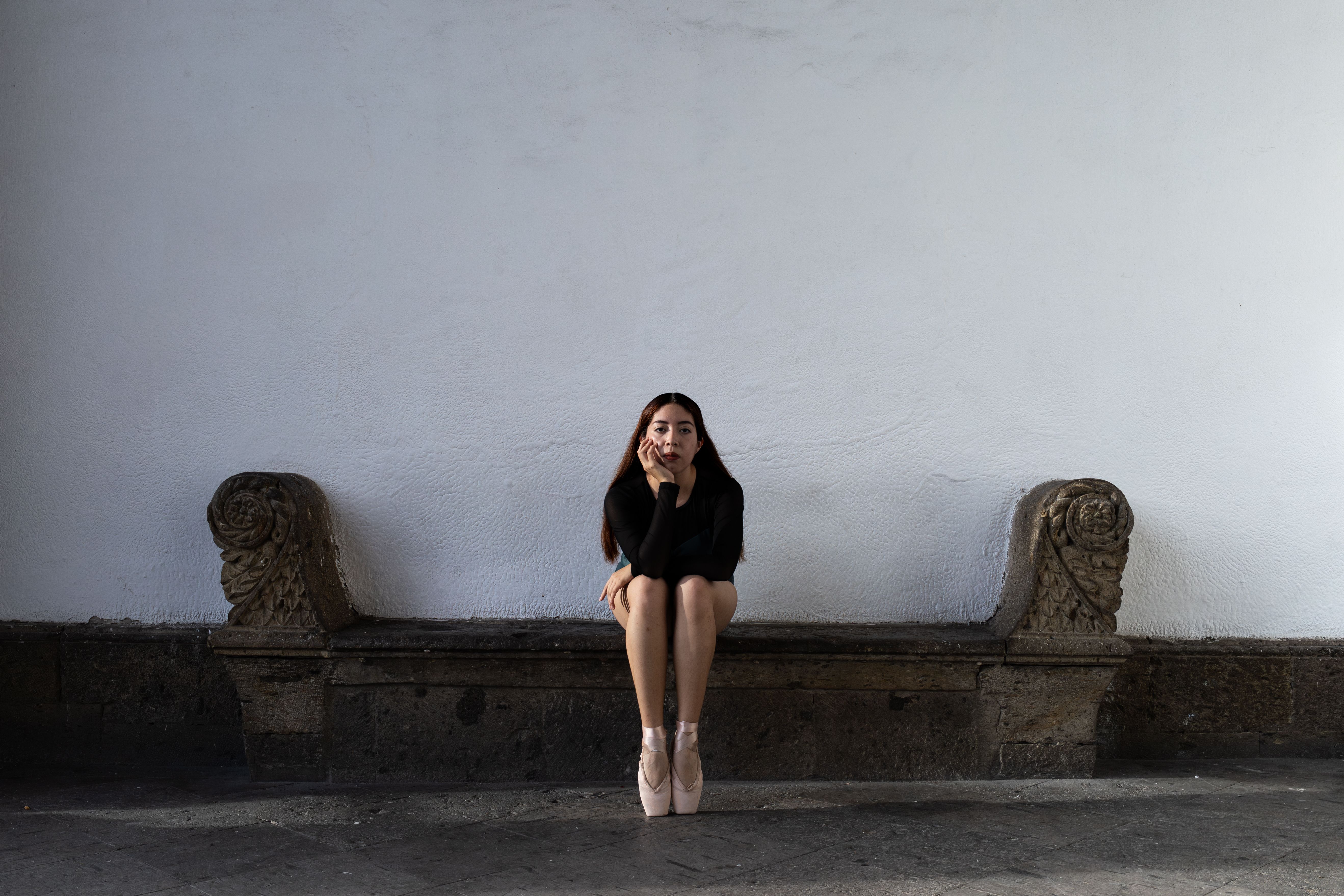 Woman in a wall sit with thighs parallel to ground, showing lower body isometric strength hold against wall.
