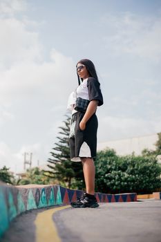Stylish woman in urban skater park with graffiti, fashion-forward look.