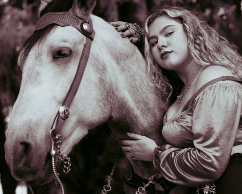 Free A young woman with curly hair affectionately holds a white horse, evoking tranquility and connection. Stock Photo