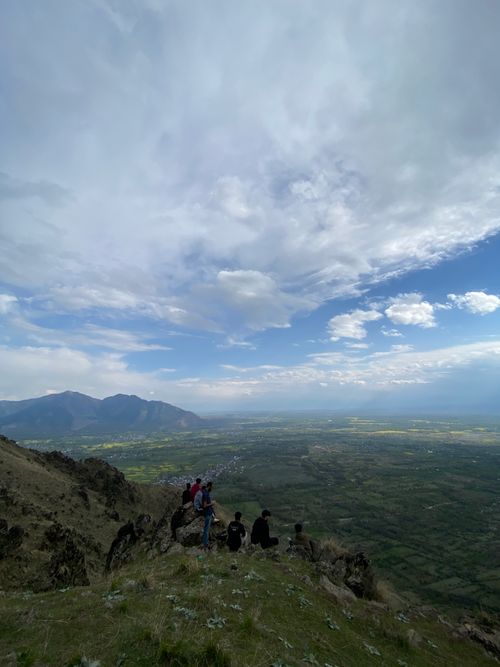 Free Group of hikers enjoying a stunning mountain view with expansive valley and clouds overhead. Stock Photo