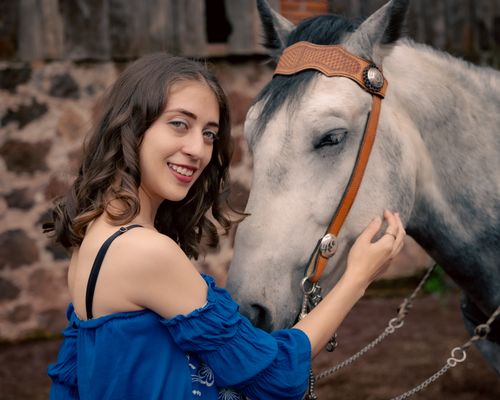 Free A young woman with curls shares a gentle moment with a white horse outside. Stock Photo