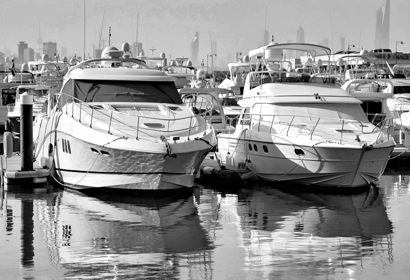 Luxury motor yachts docked at an urban marina with city skyline in the background