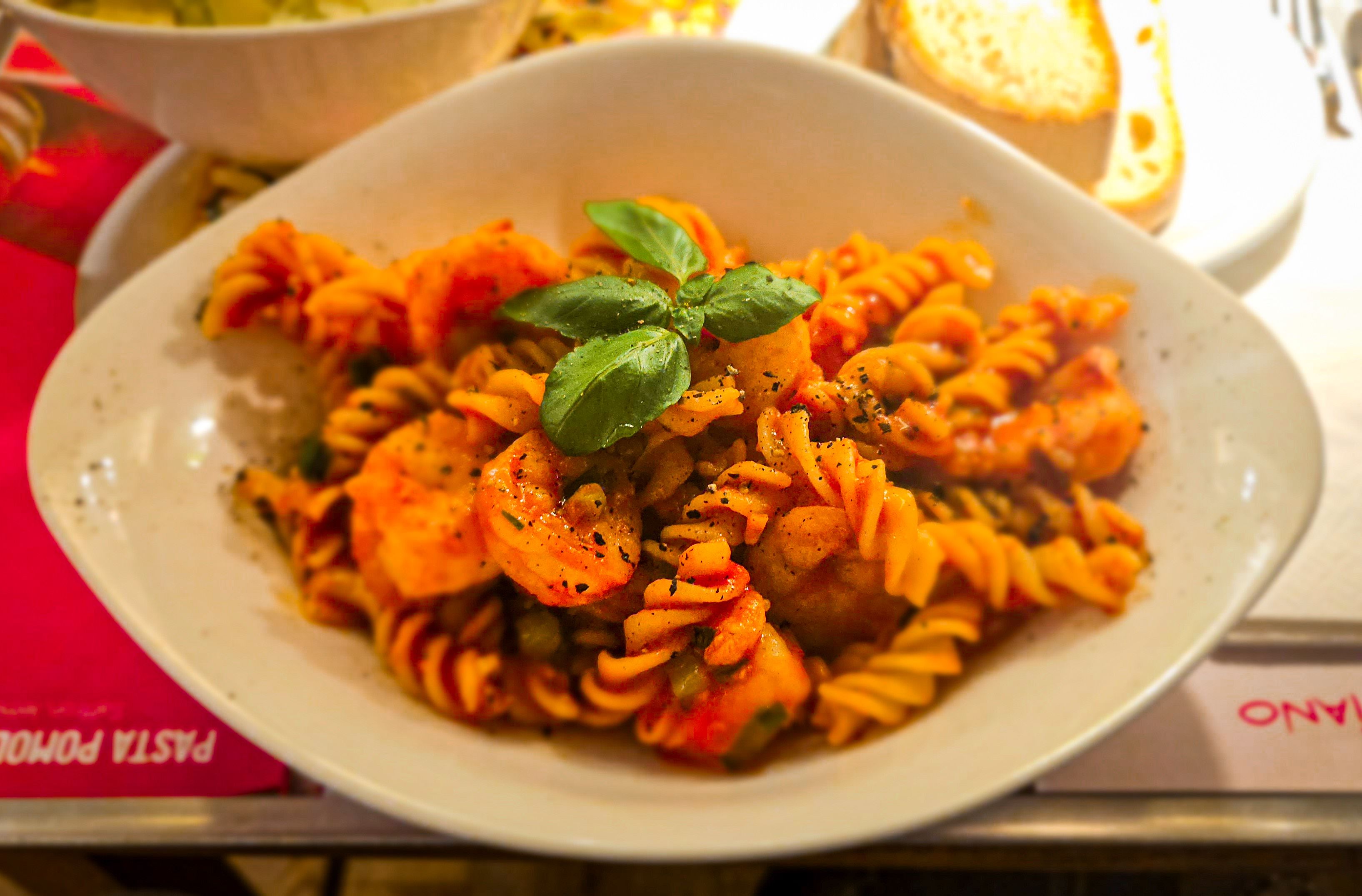 A mouthwatering dish of fusilli pasta with seafood and fresh basil garnish, perfect for foodies.