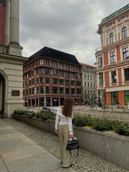 A woman walks along a European city street with historic architecture.