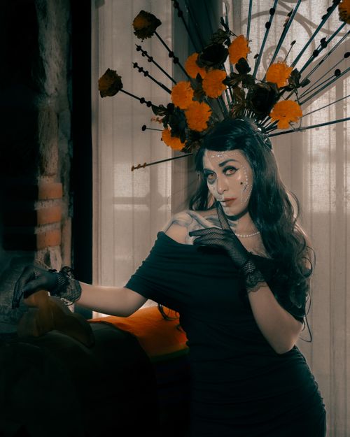Free A woman in Catrina makeup with an ornate headdress celebrates Día de Muertos indoors. Stock Photo