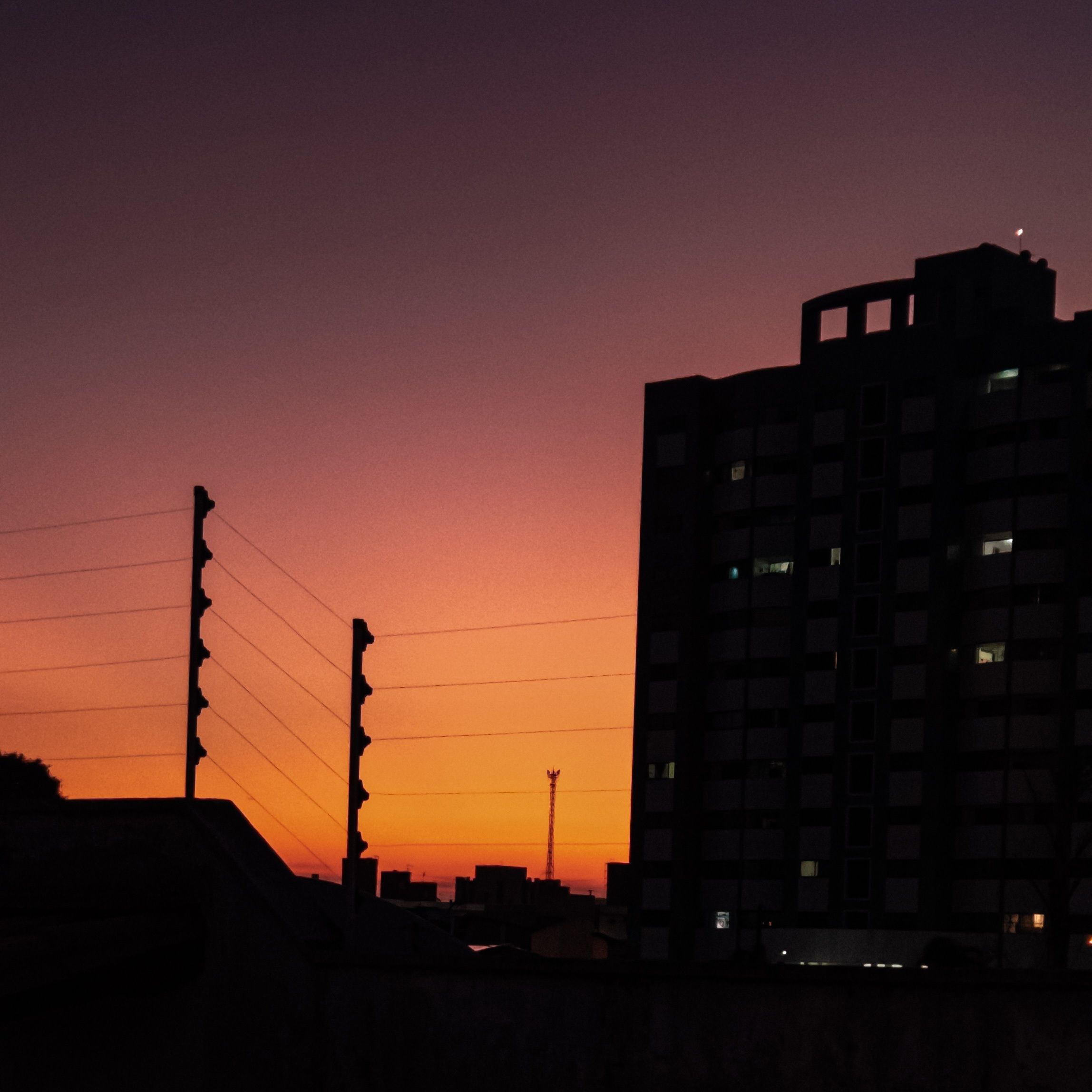 Dramatic cityscape at sunset with silhouetted building and colorful sky.