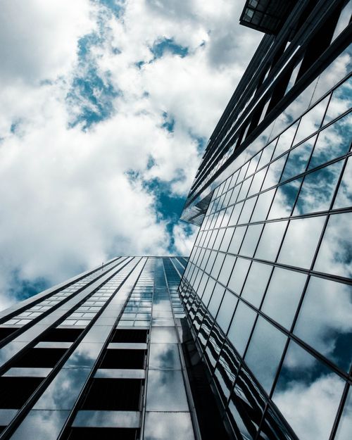 Free A striking view of a glass skyscraper reflecting the sky in Rotterdam, Netherlands. Stock Photo