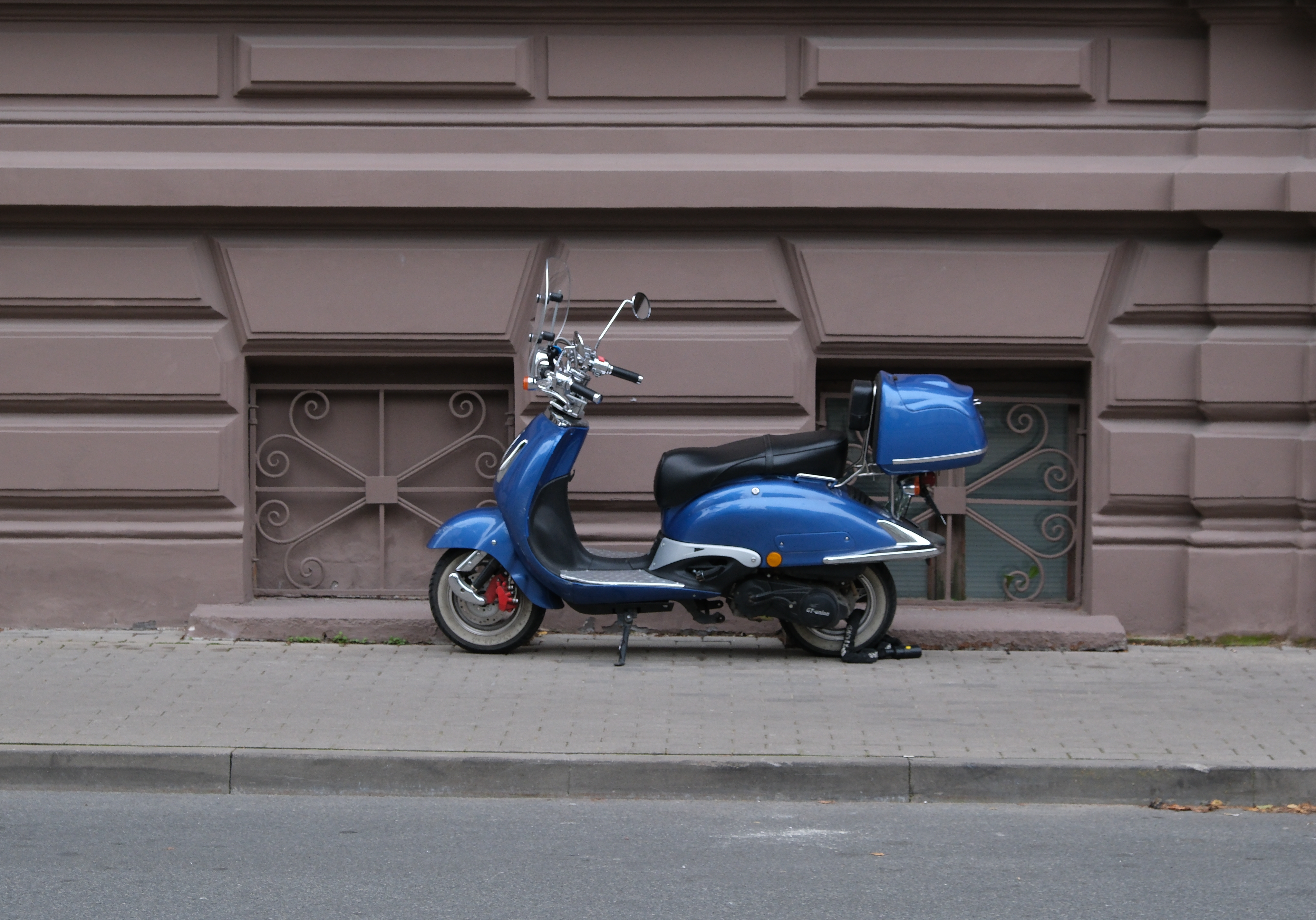 Blue moped parked by an ornate historic building in Riga, Latvia, showcasing urban architecture.