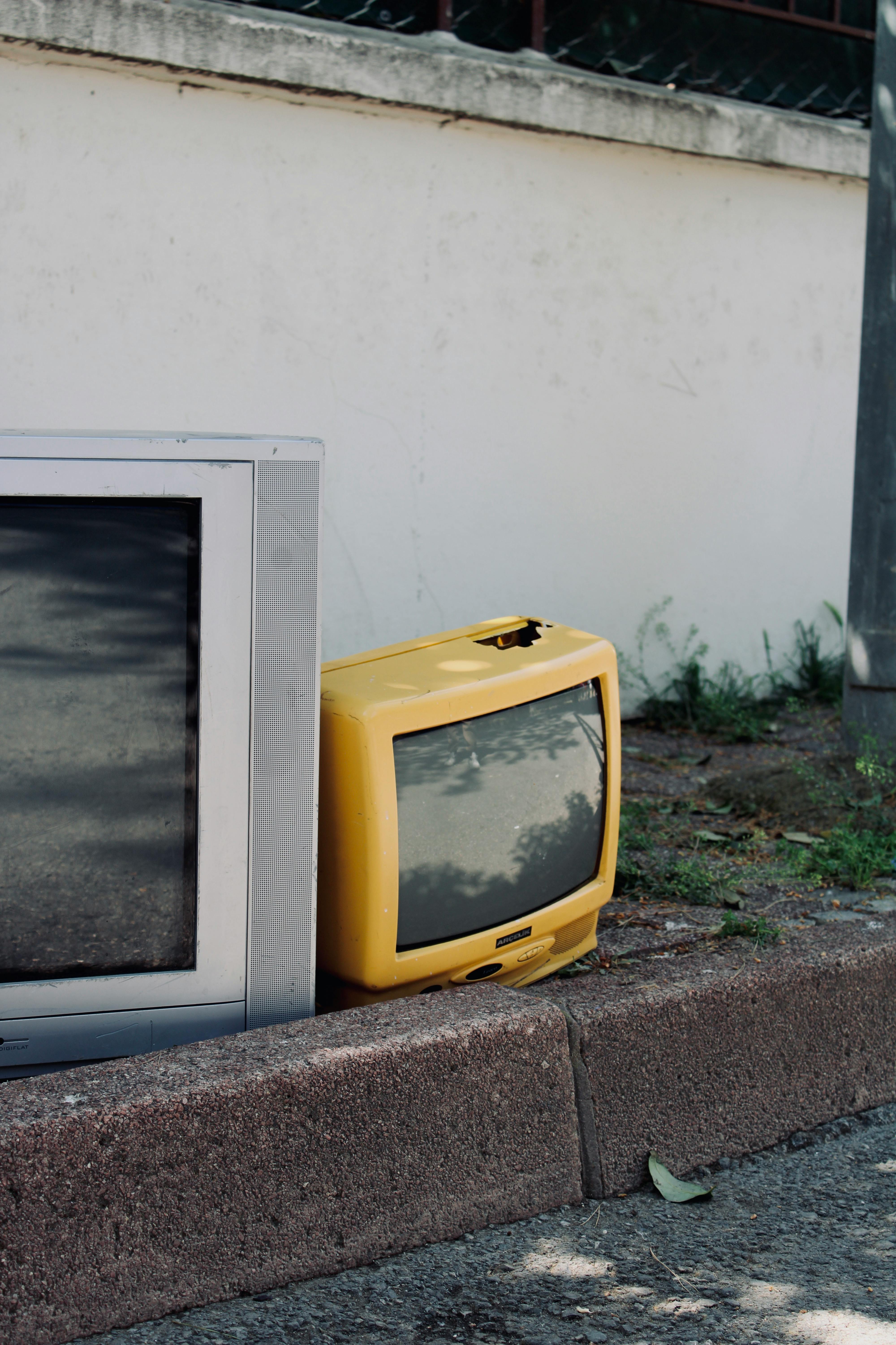 Two old TVs left on pavement, highlighting electronic waste and urban decay.