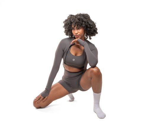Free Confident woman in stylish gray athletic wear posing against a white backdrop. Stock Photo