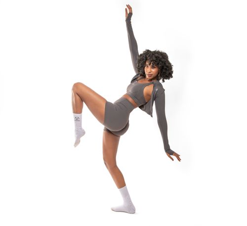Free Woman in gray athletic wear performing a dynamic pose against a white background. Stock Photo