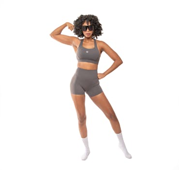 A woman in stylish athleisure flexing her muscles, exuding confidence and strength.