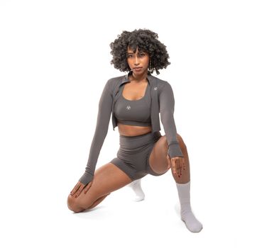 Athletic woman in stylish workout gear posing against a white background.