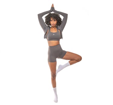 Woman in grey activewear doing yoga pose on white background, showcasing flexibility and strength.