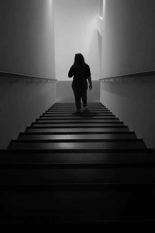 Free Person walking up dark stairwell, modern minimalistic architecture Stock Photo