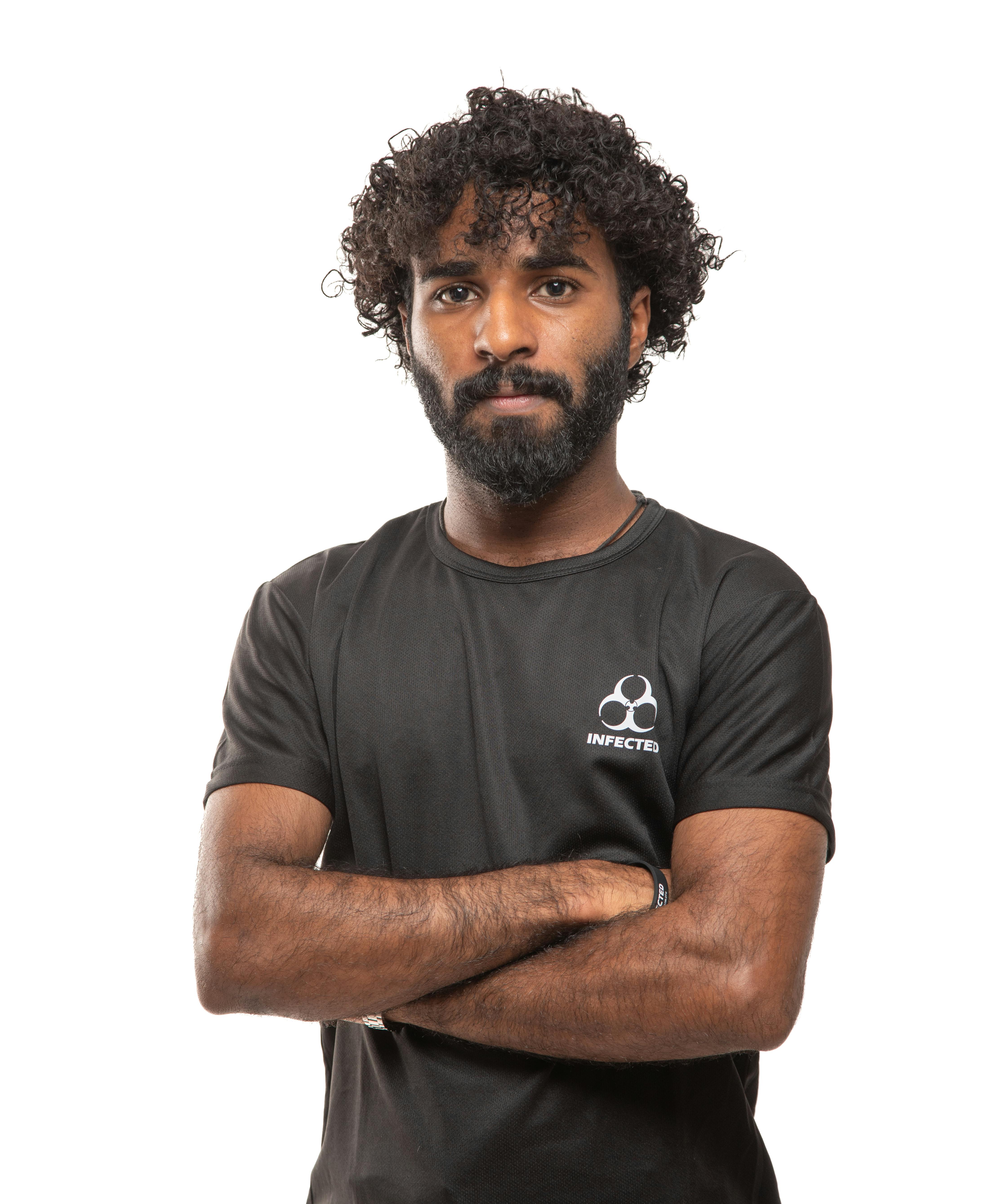 Portrait of a confident man with curly hair wearing a black sports t-shirt featuring biohazard symbol.