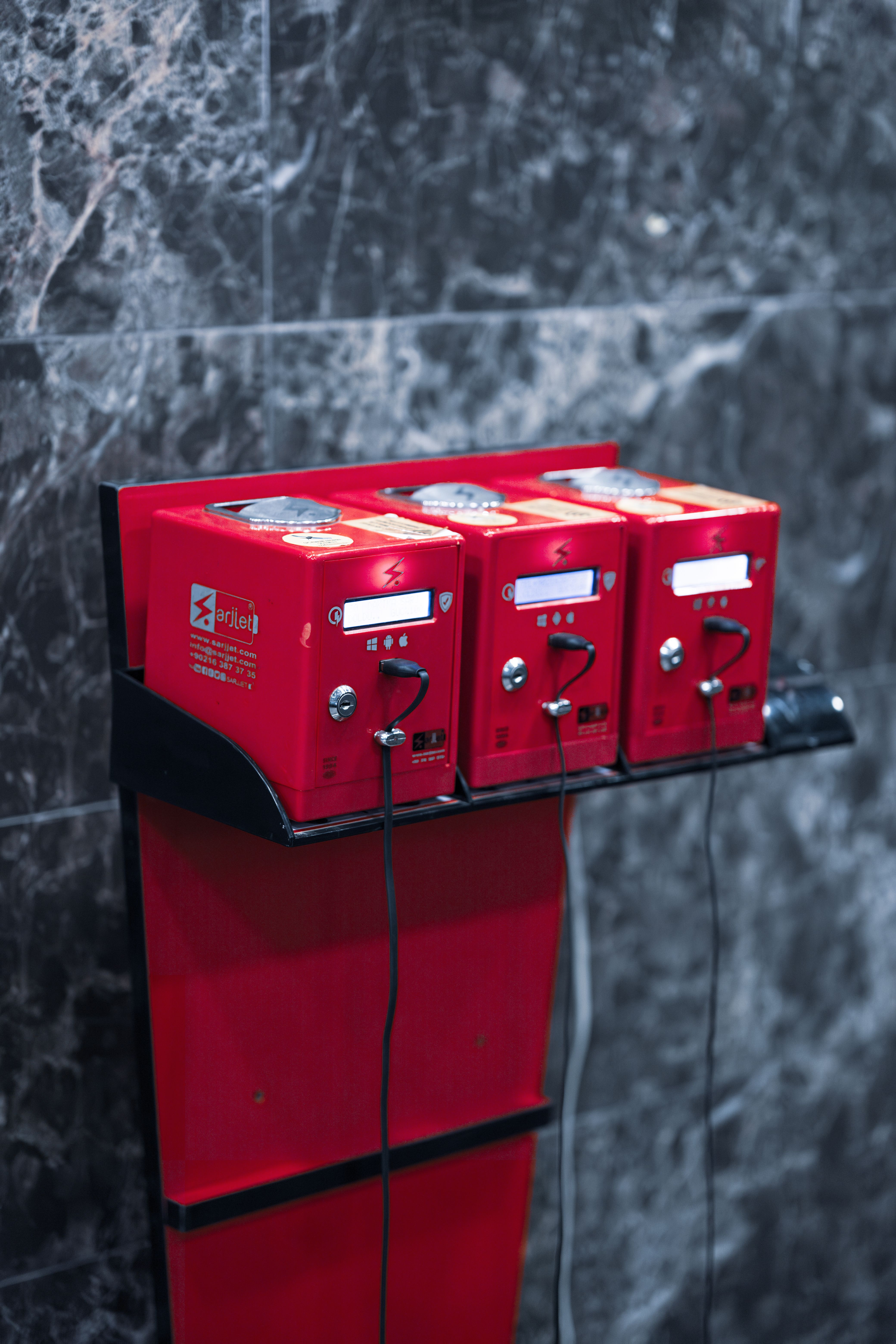 Three vintage red coin-operated public telephones mounted on