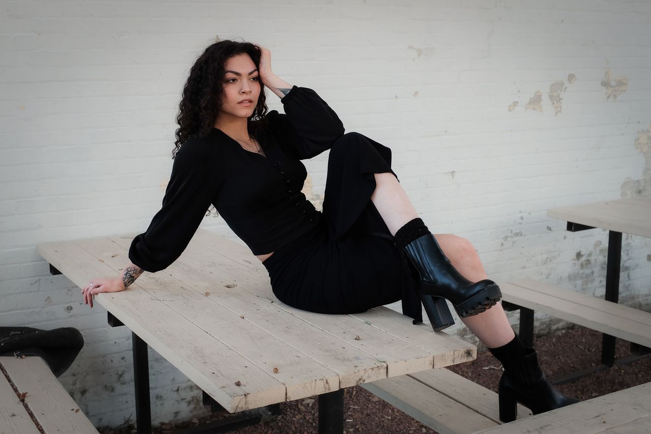 fashionable woman dressed in black sitting confidently on an outdoor b