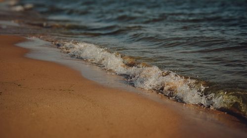 Free Peaceful beach scene with gentle waves washing over sandy shore at daytime. Stock Photo