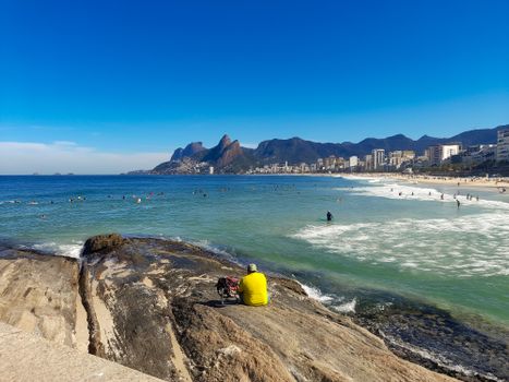 A scenic view of Ipanema Beach in Rio with city skyline and beachgoers.