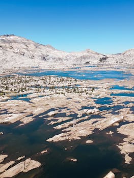 Aerial shot of California's rugged terrain with desolate islets and a vivid blue sky.