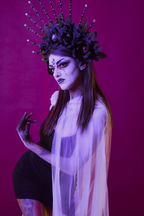 Free A dramatic portrait of a gothic model in floral crown against a vivid background. Stock Photo