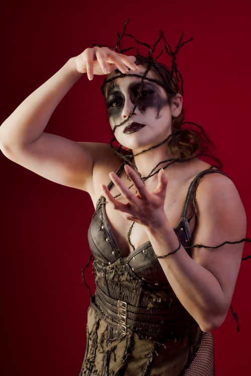 Free A striking performer in gothic makeup and costume, set against a bold red background. Stock Photo