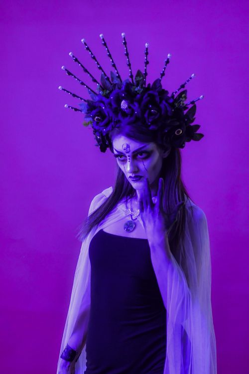 Free A woman with a detailed headdress and face paint in a magical purple setting. Stock Photo