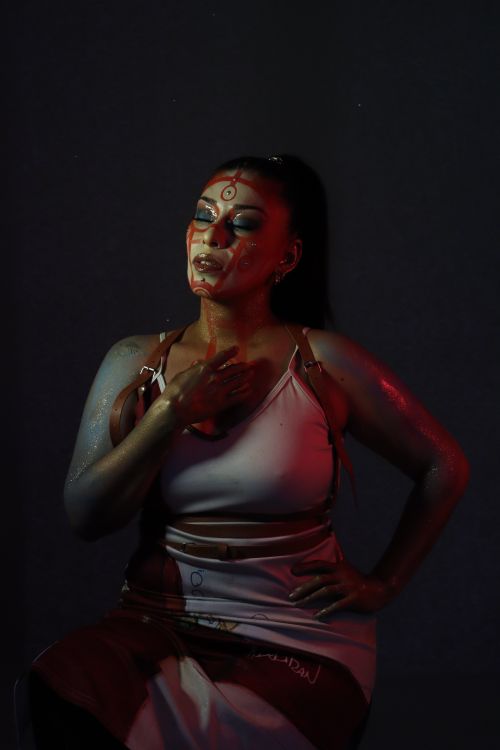 Free Moody artistic portrait of a woman with vibrant face paint under dramatic lighting. Stock Photo