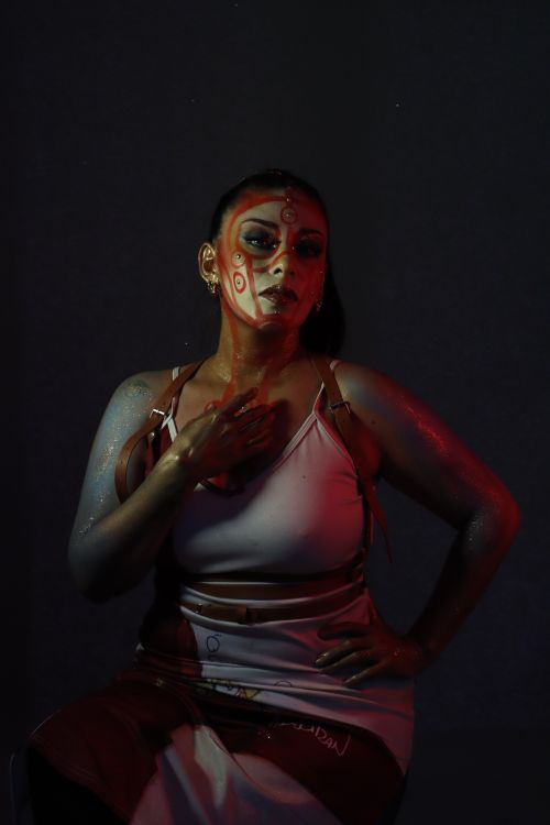 Free A striking portrait of a person in face paint under dramatic red lighting. Stock Photo