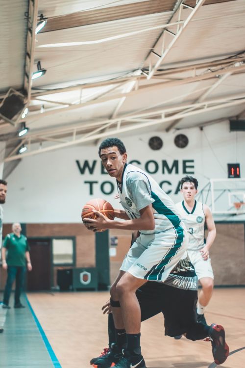 Free Energetic capture of young male basketball players in action during an indoor game. Stock Photo