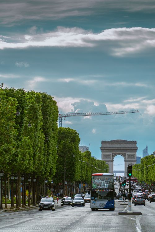 Free Vibrant Parisian street scene featuring traffic and the iconic Arc de Triomphe. Stock Photo