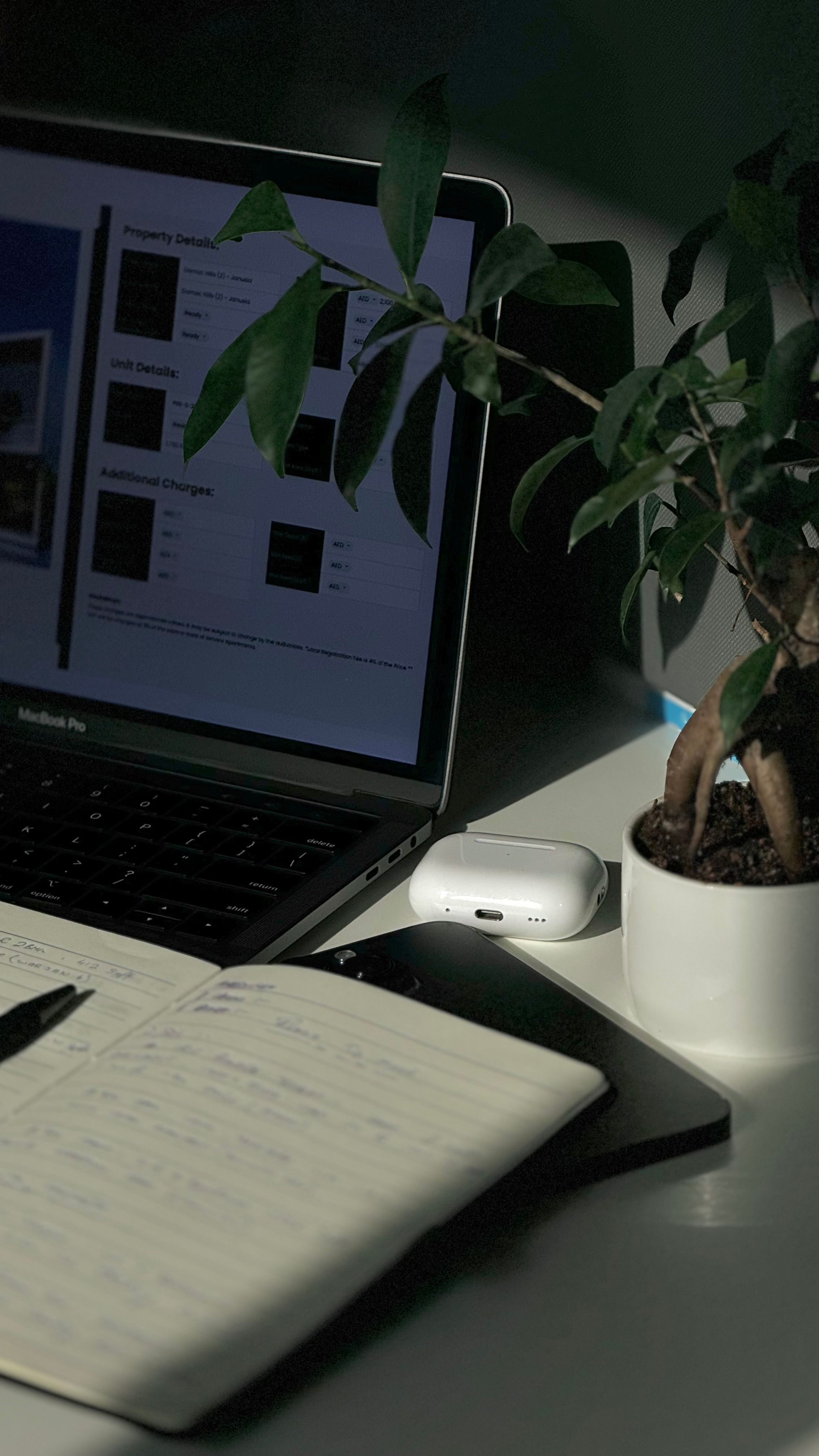 A notebook and pen resting on a dark desk beside a warm study lamp