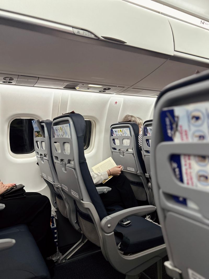 Passenger reading a book in an airplane seat