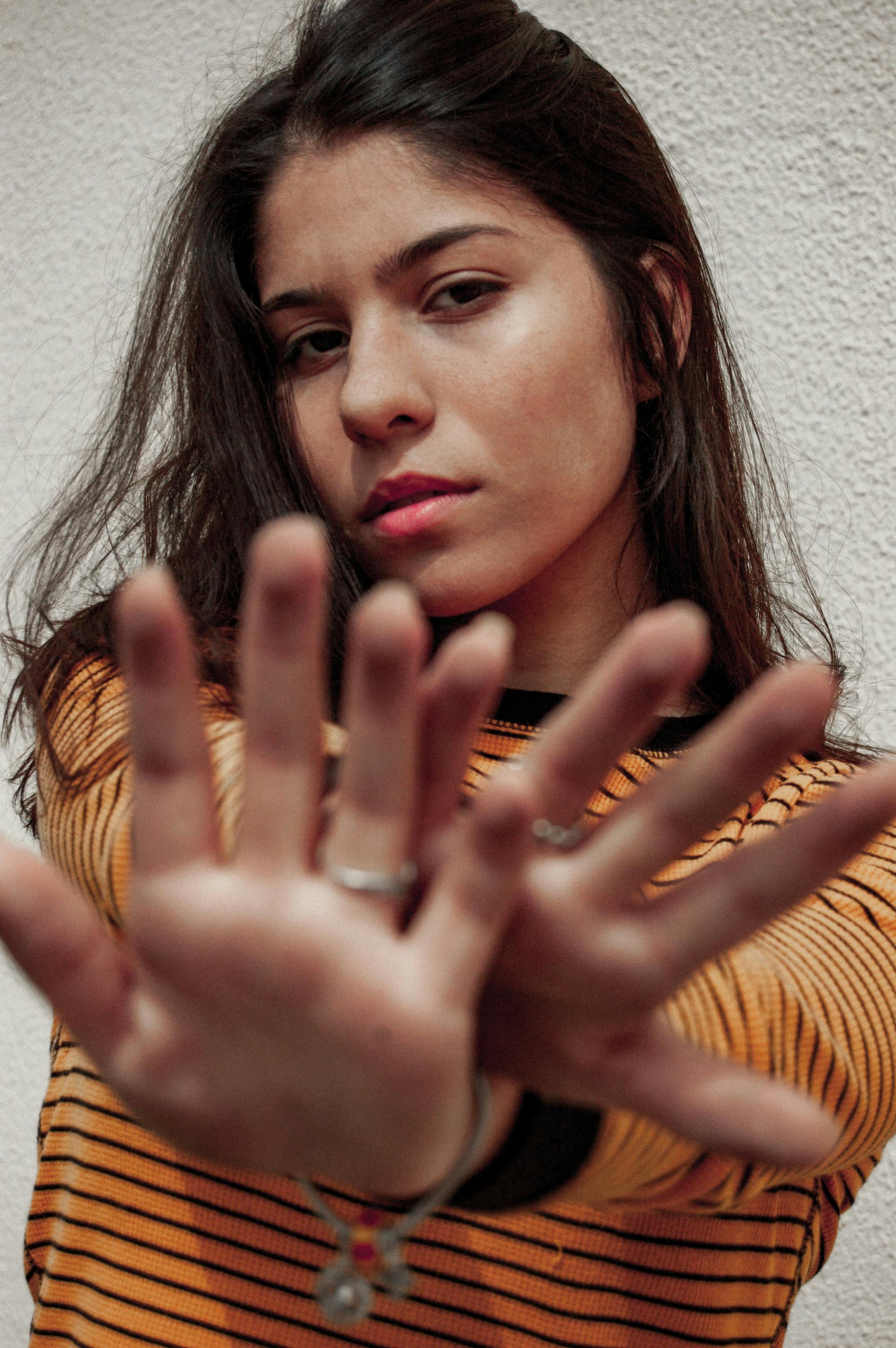 一位时尚的年轻女子穿着条纹毛衣，伸出双手摆姿势的肖像