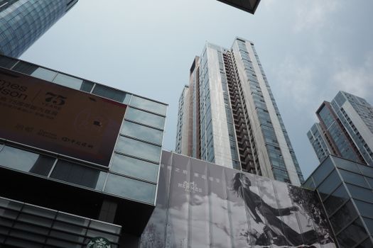 Skyscrapers with commercial billboards under a cloudy sky, depicting a modern urban scene.