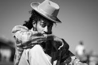 一位时尚男士戴着帽子，在户外摆出黑白姿势，尽显时尚与优雅