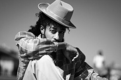 Free A fashionable man with a hat poses outdoors in black and white, showcasing style and elegance. Stock Photo
