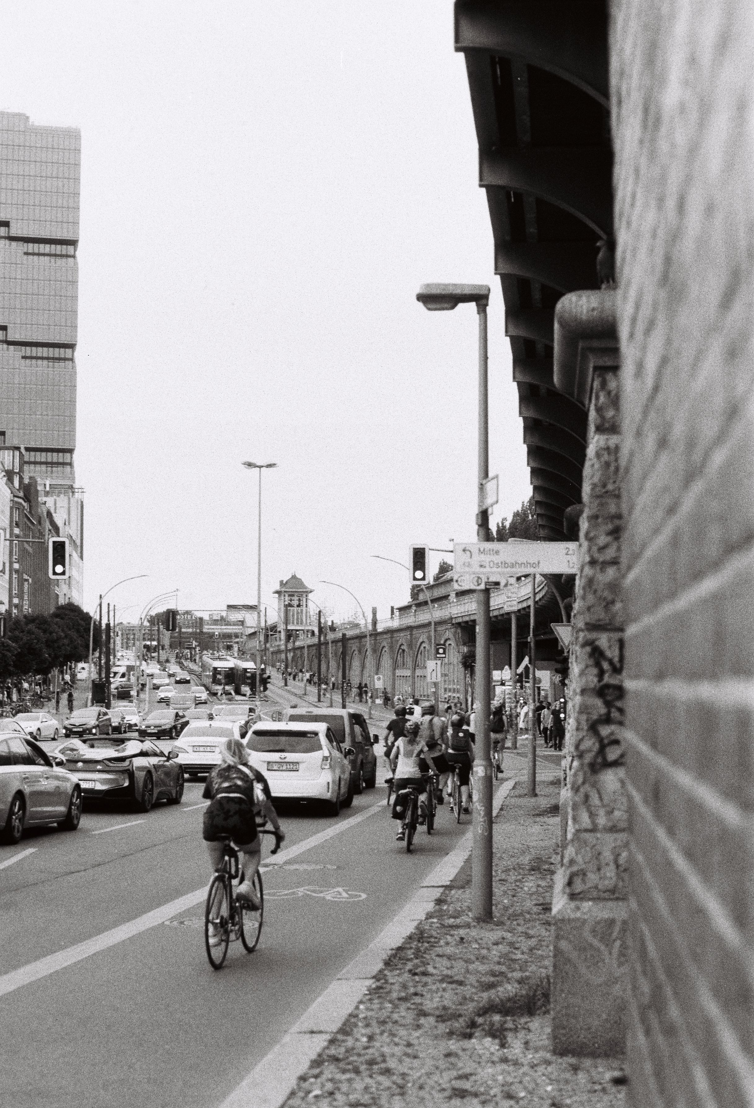 Black and white street view in Berlin showcasing cyclists and urban traffic on a busy day.