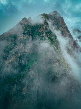 A dramatic mist-covered mountain peak emerges through clouds, showcasing ethereal scenery.