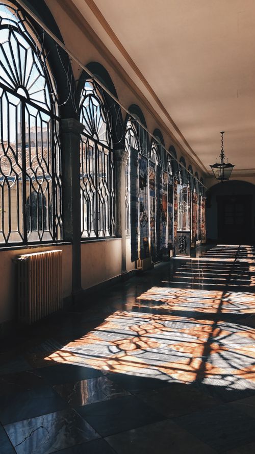Free Elegant vintage hallway with intricate windows casting enchanting shadows in Granada, Spain. Stock Photo