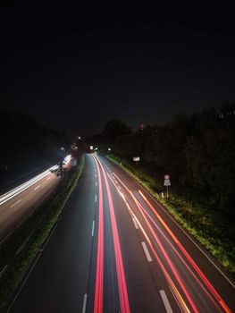 Long exposure shot of highway traffic at night, capturing vibrant light trails and dark serene surroundings.