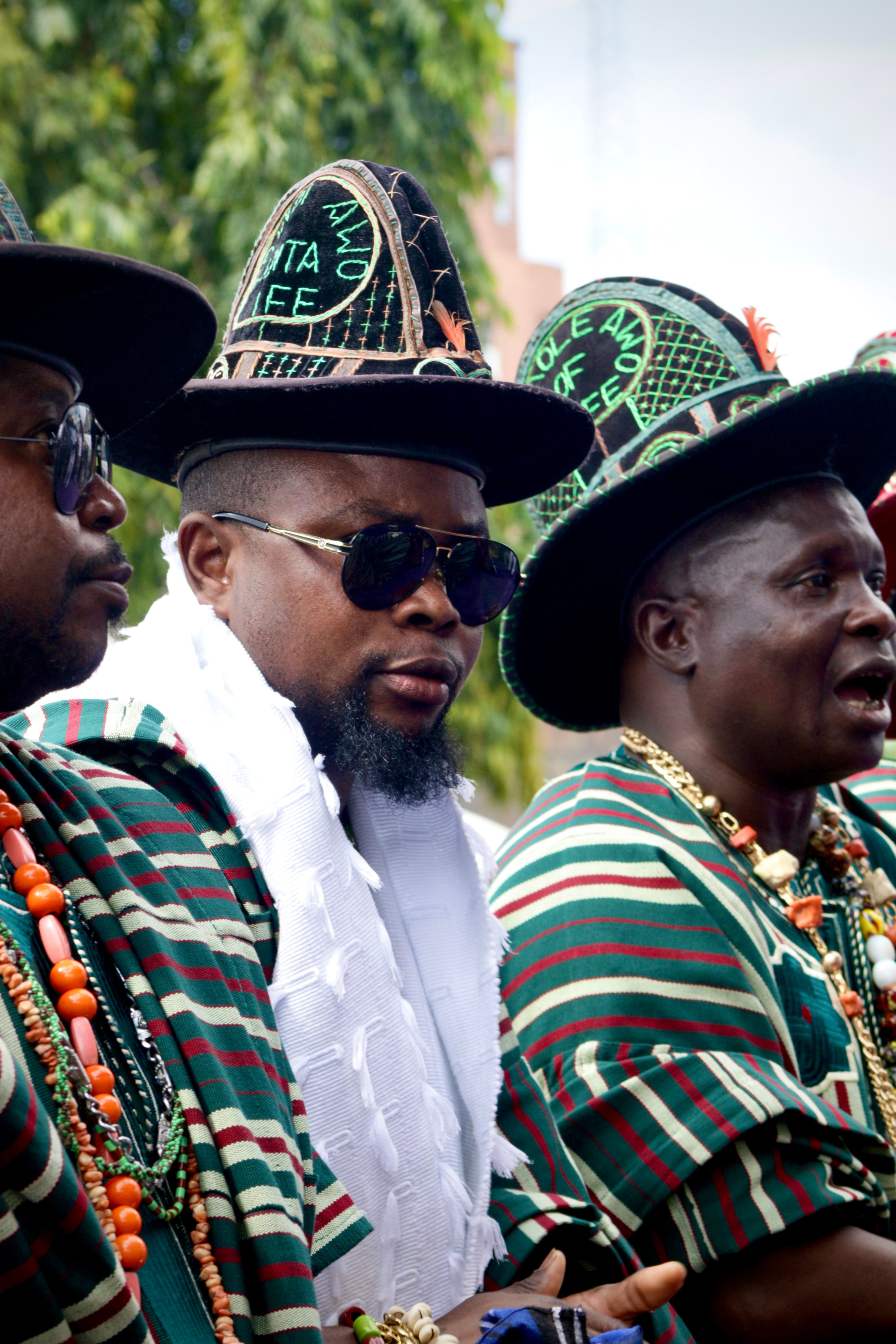 Men in traditional African attire and hats at a cultural festival showcasing heritage and identity.
