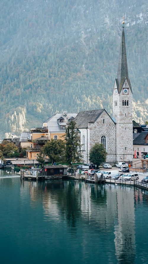 Free Scenic view of a church and village by a tranquil mountain lake in Hallstatt. Stock Photo