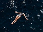 一个穿着泳装的女人勇敢地踏入深蓝色的海洋，展现优雅与自由