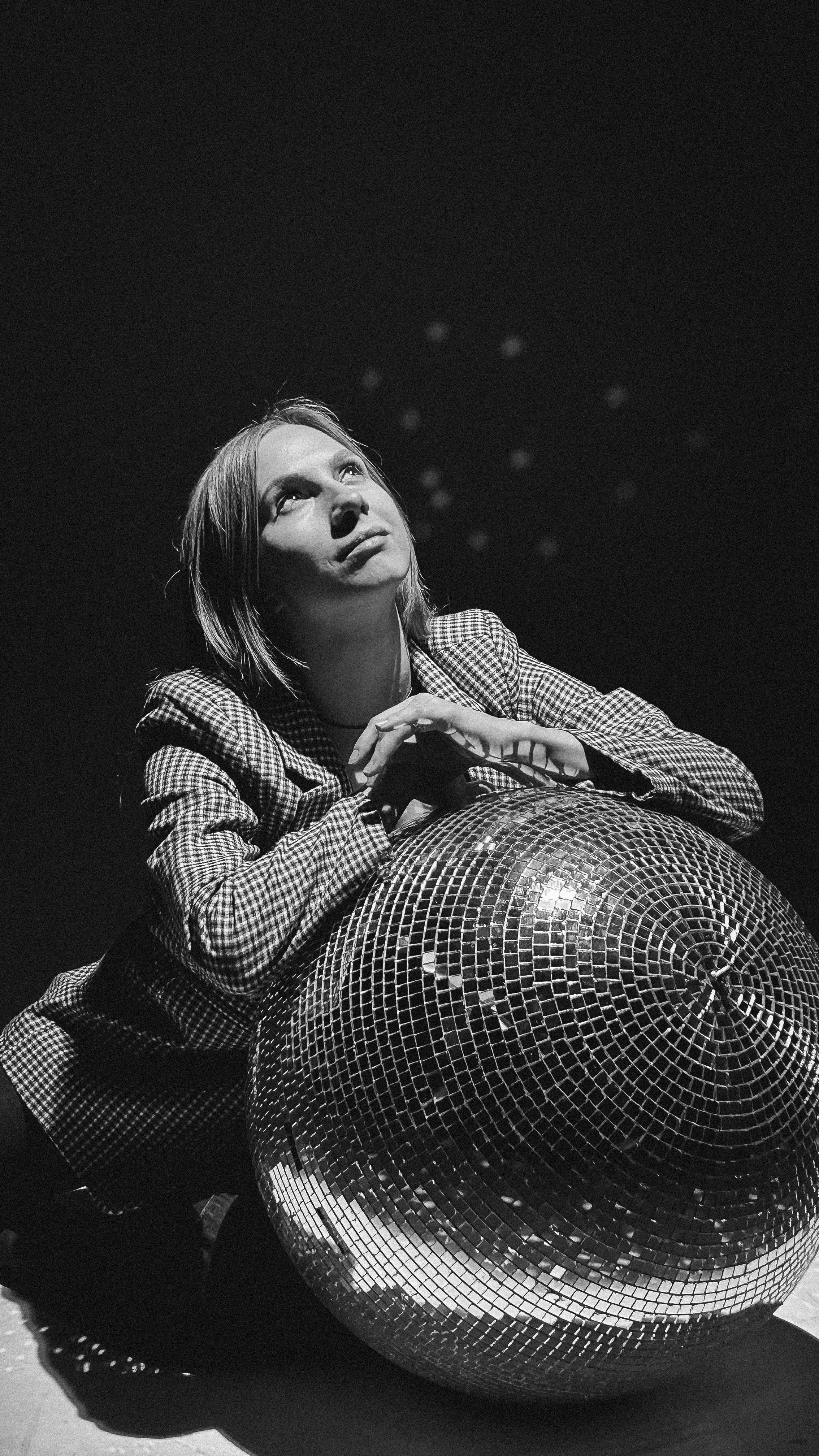 Woman in checkered suit with disco ball, black and white artistic photo.