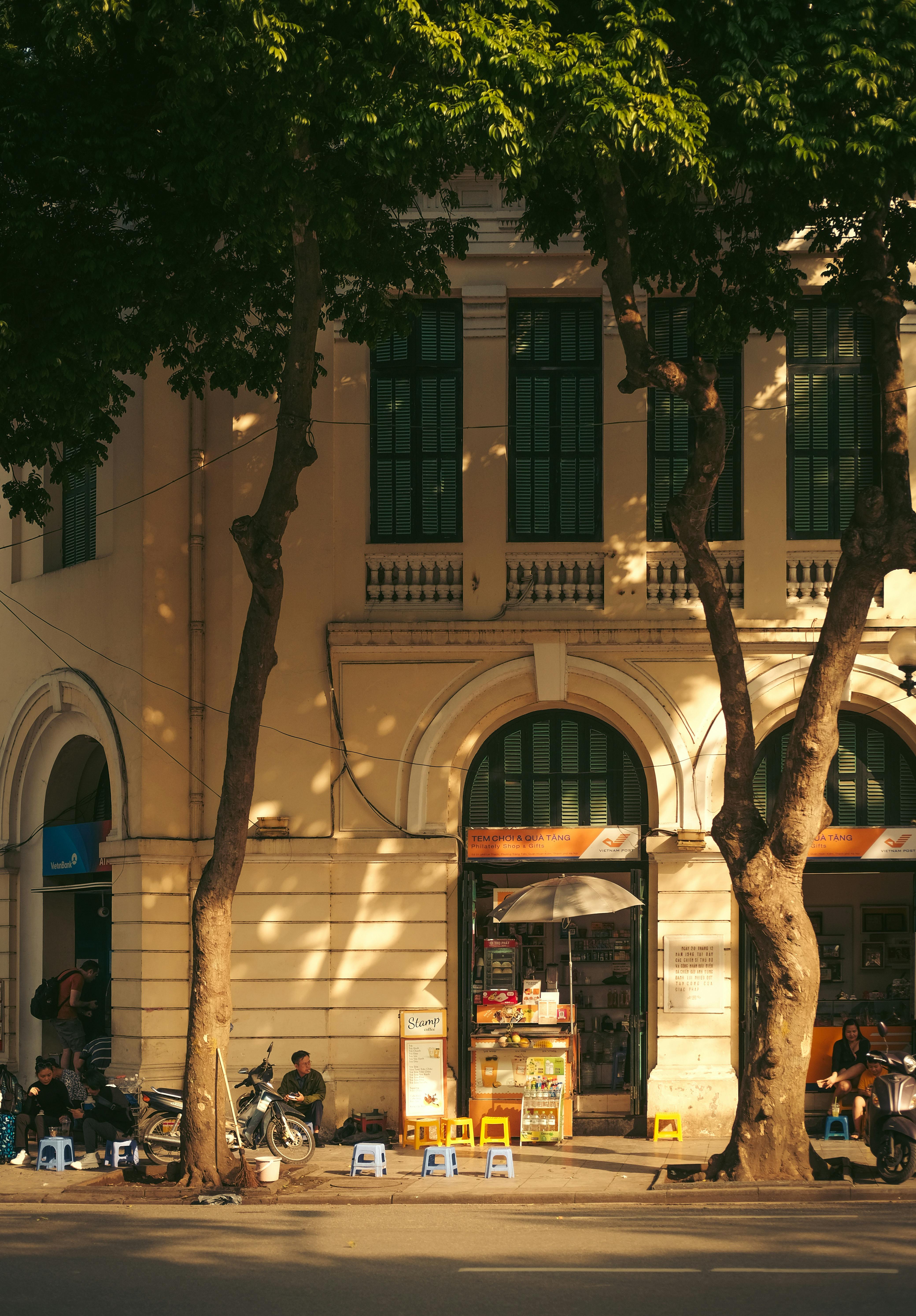Sunlit afternoon street scene in Hanoi, featuring a classic colonial building.